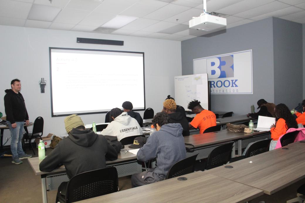 A group of people sitting in a classroom listening to the instructor