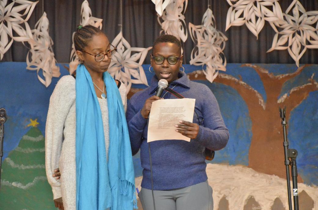 Two women on stage reading remarks on a paper.
