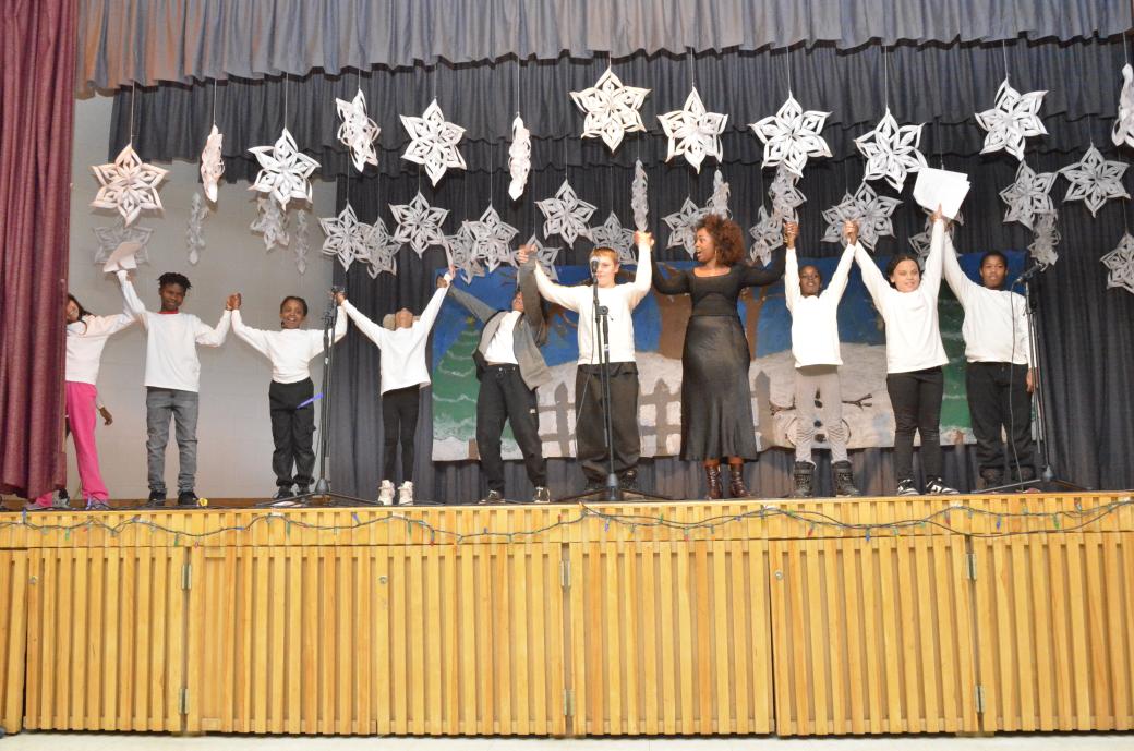 A group of individuals holding hands on stage.
