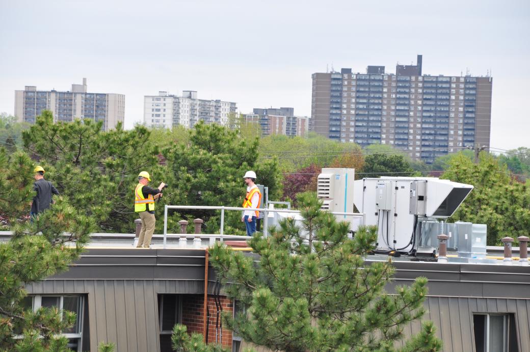 people in safety vests on the roof of the sparroway community
