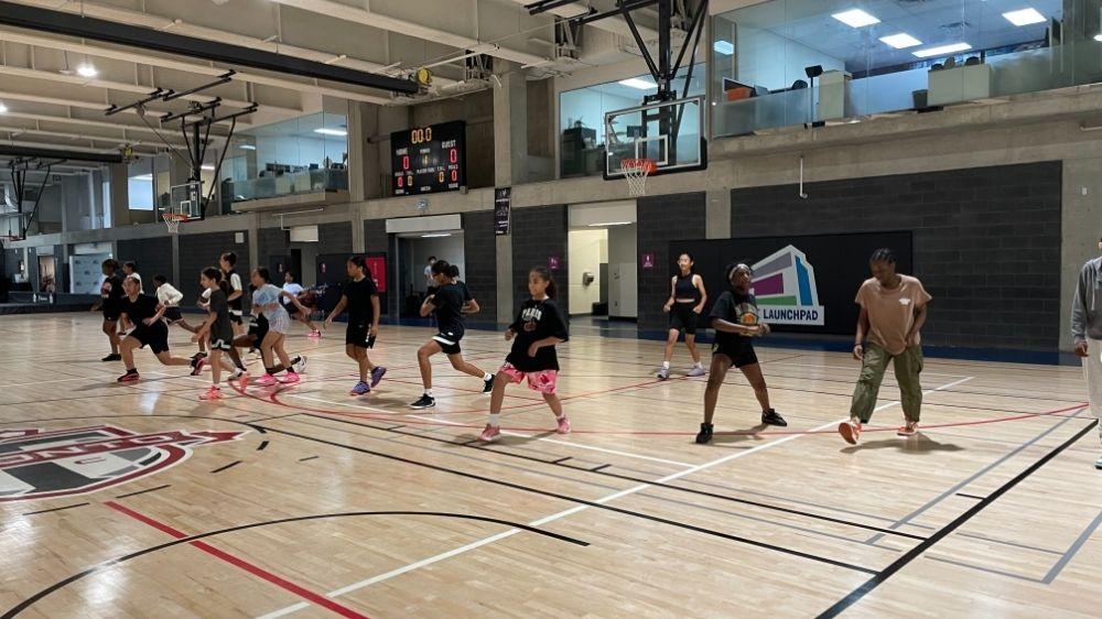 A group of young girls exercising on a basketball court.
