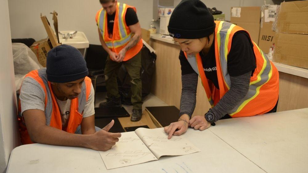 A group of young people looking at instructions in a book.
