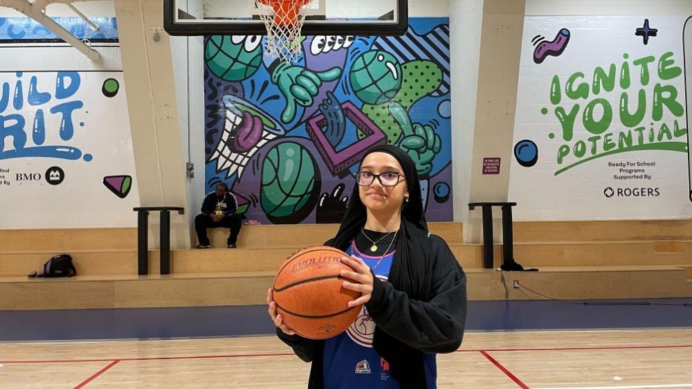 A person holding a basketball in a gymnasium.