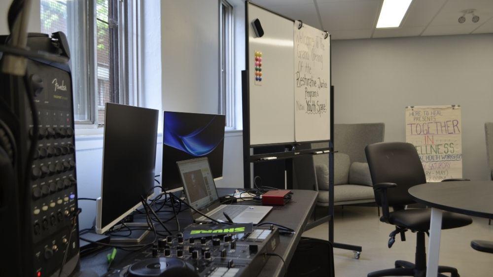 A photo of a room with a whiteboard, a laptop, monitors and studio equipment.