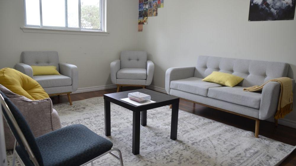 A photo of a room with grey sofas, yellow pillows and chairs