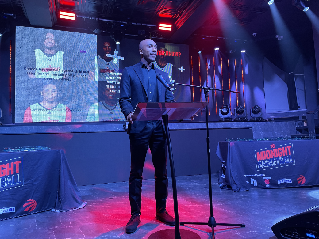 Person standing in front of a microphone speaking to an audience