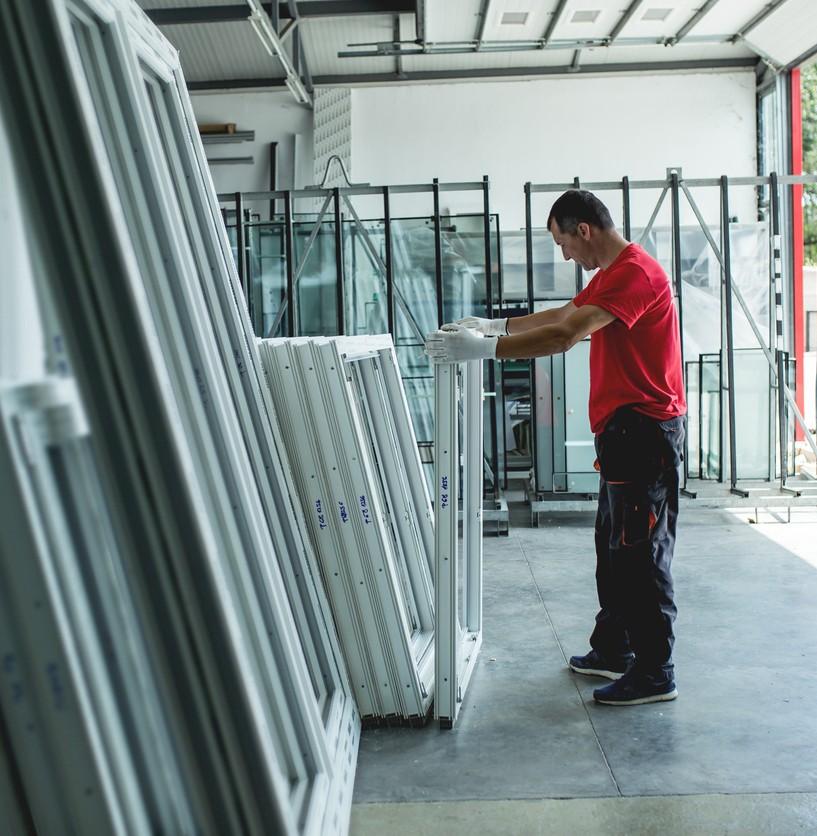 A worker in an open warehouse of aluminum window panes