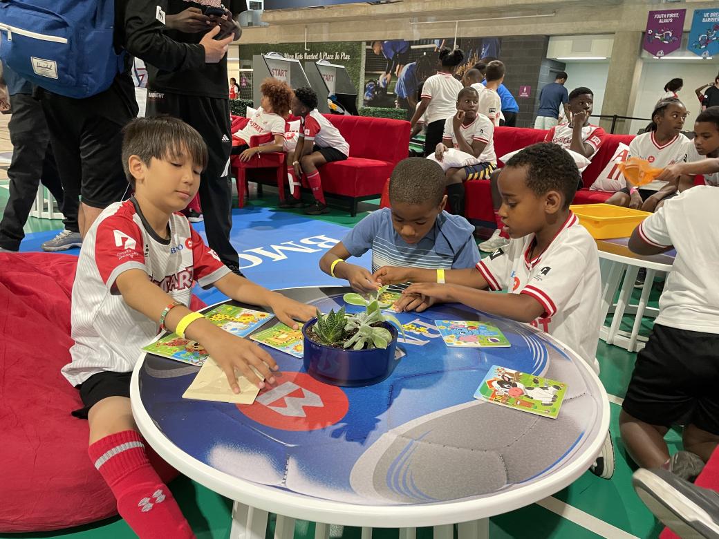 A group of children in athletic outfits sitting at a table enjoying activities.
