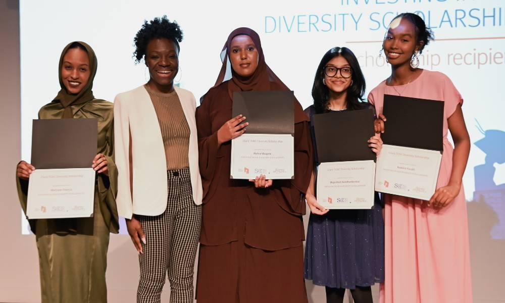 Four scholarship recipients stand on stage with a TCHC staff member.
