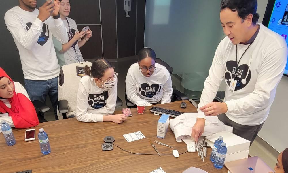 Dr. Robert Yanagawa leading a workshop demonstration in a board room with Next Gen Surgeon students.