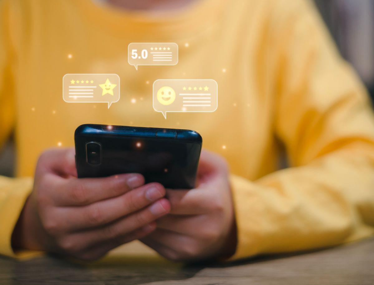 A person holding a smartphone. Review bubbles appear above the phone.