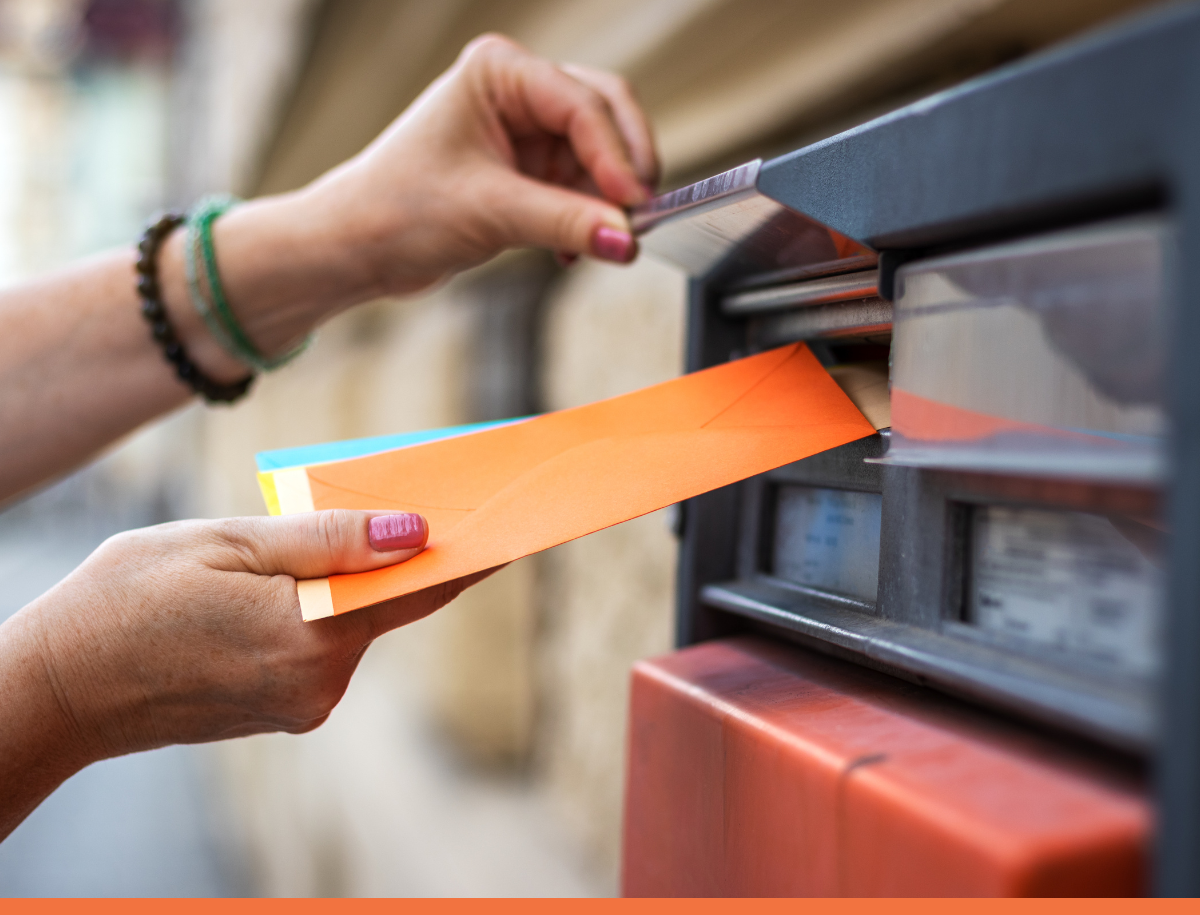 A person putting mail into a mailbox.