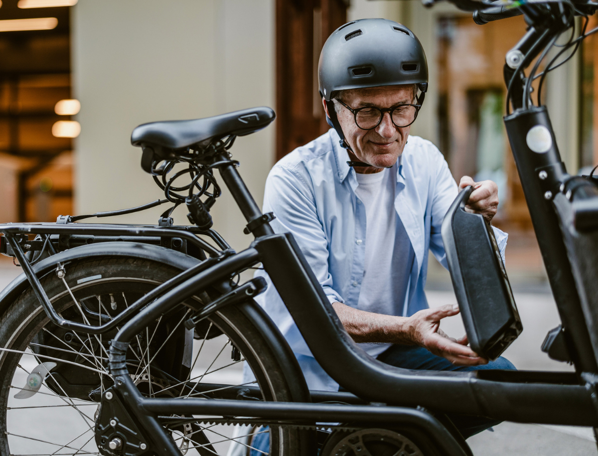 A person crouching down to replace a battery on an electric bike