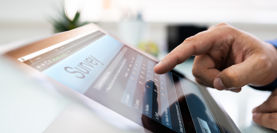 Right hand hovering over tablet screen that says survey.