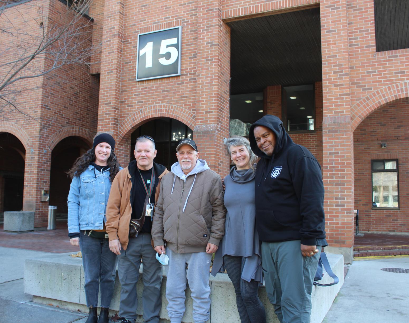 Group shot of five people standing outside a building
