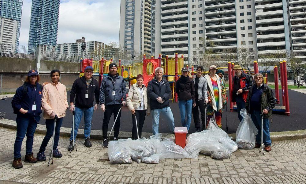 A group of tenants are shown with garbage bags in the foreground and highrise buildings in the background