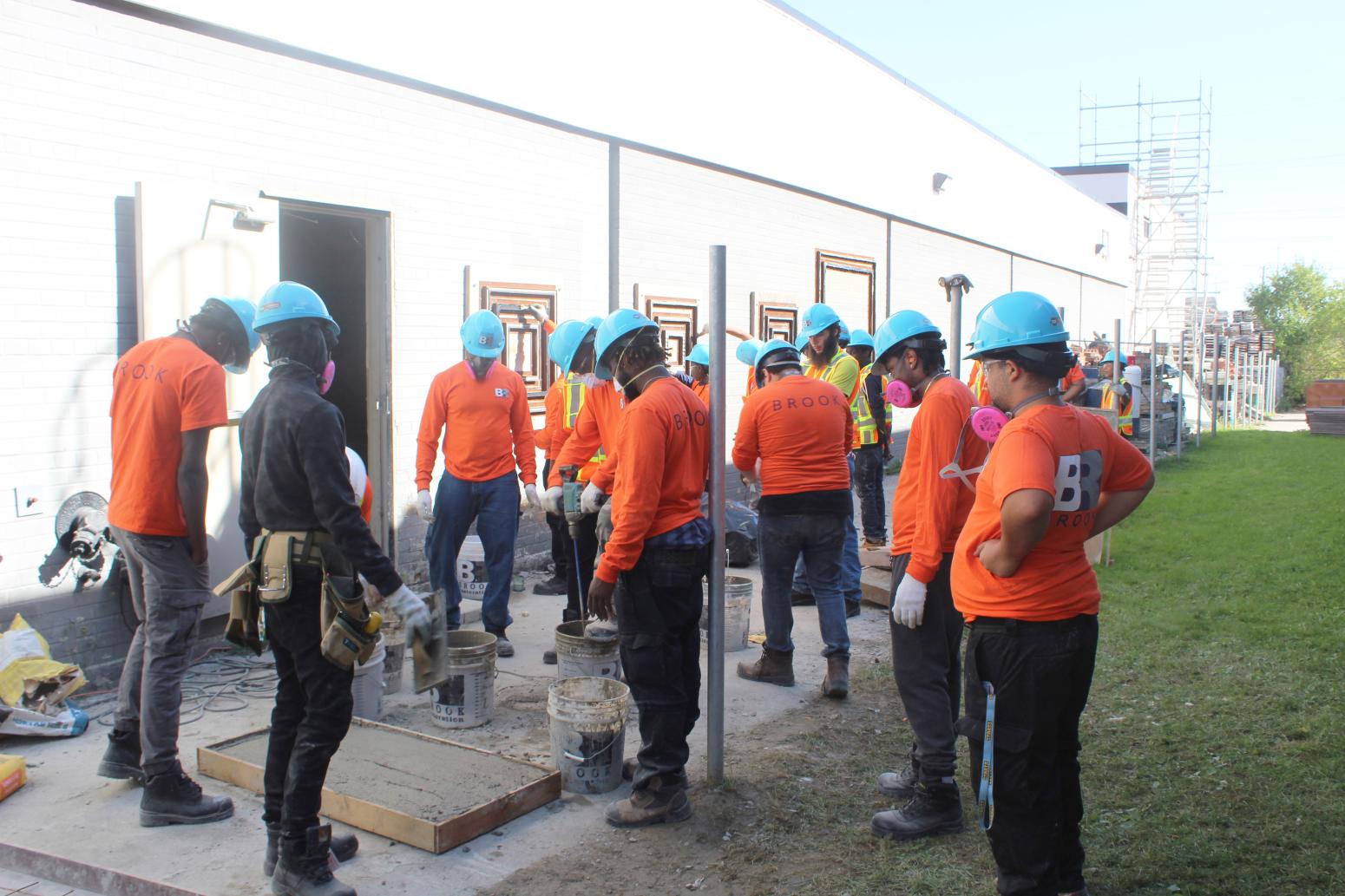 A group of people wearing orange shirts and hard hats