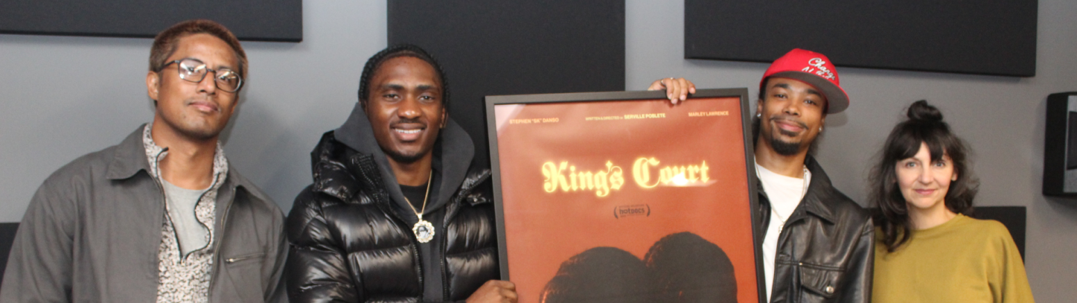 Group of four people, with two carrying a poster that says King's Court on it. 