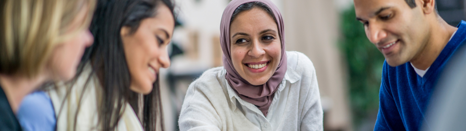 Four people sitting together smiling and talking.
