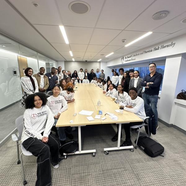 Photo showing a group of students sitting around a table in a boardroom