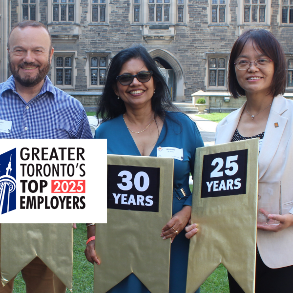 Three TCHC employees standing outside Hart House, holding signs with their years of service