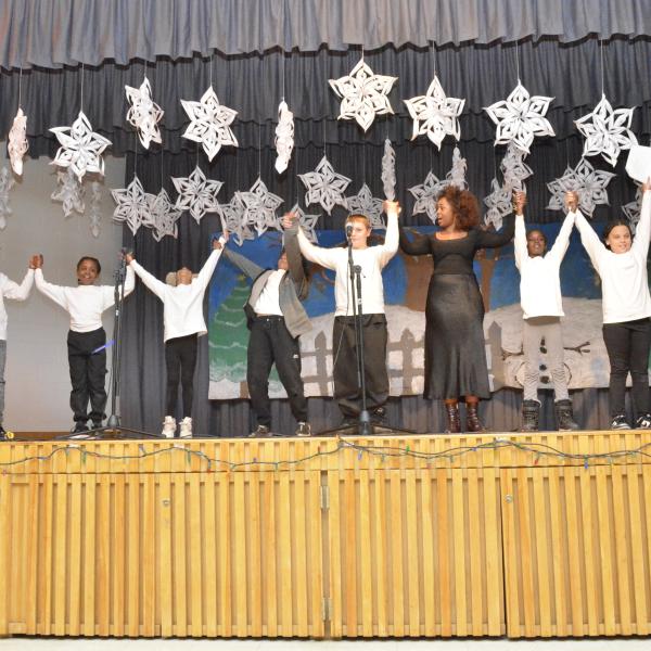 A group of individuals holding hands on stage.     