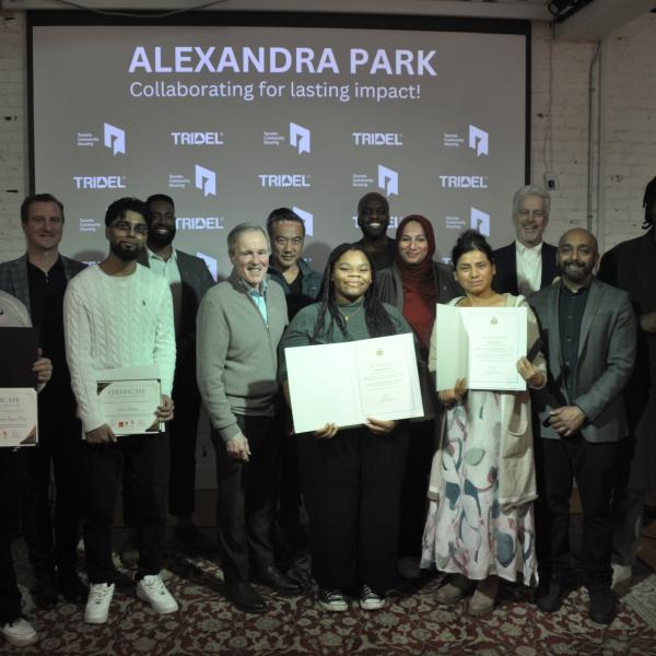 Group of Alexandra Park scholarship recipients standing in front of the room with the presentation as backdrop